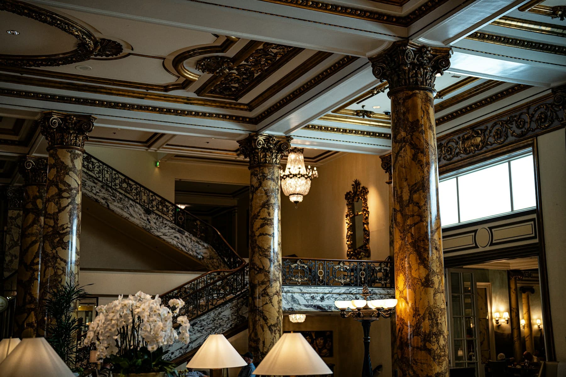 Marble columns and a chandelier in a hotel lobby.